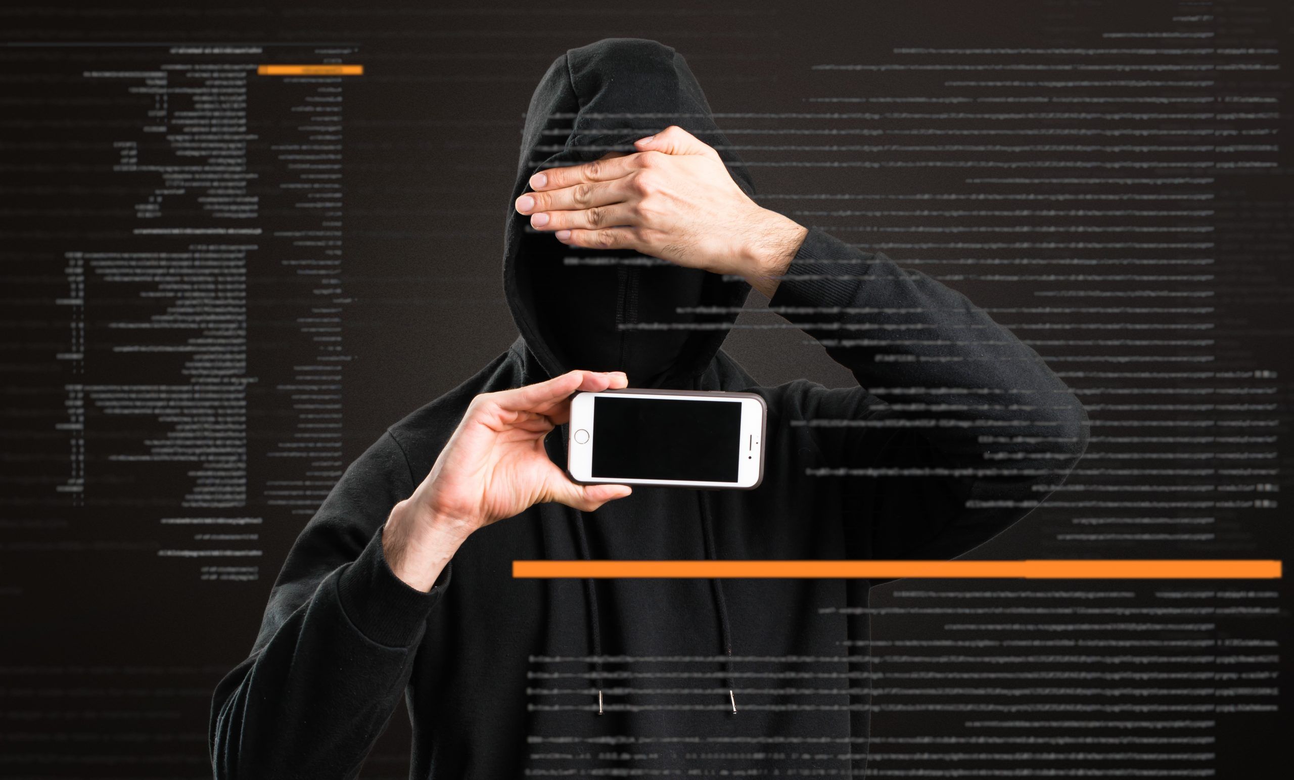 Hacker with his mobile covering his face on dark background